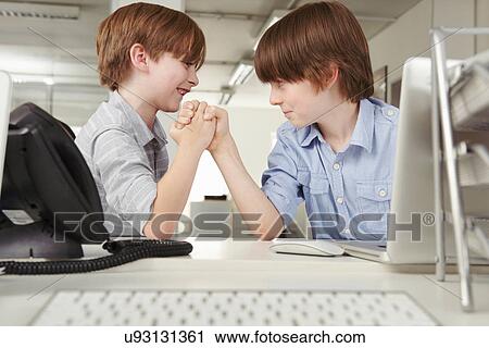 Two boys arm wrestling in office View Large Photo Image Stock Image - Two boys arm wrestling in office. Fotosearch