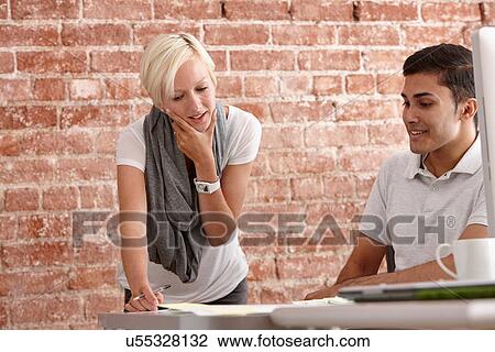Two colleagues talking at desk View Large Photo Image Stock Image - Two colleagues talking at desk. Fotosearch