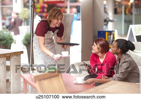 Stock Image - Two female friends having coffee in street cafe. Fotosearch