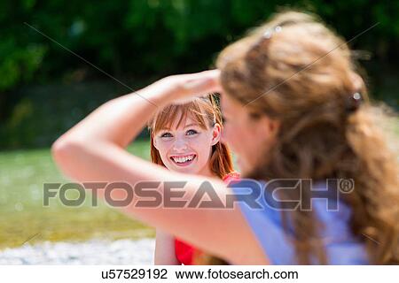 Two female friends in sunlight, one shielding eyes View Large Photo Image Stock Image - Two female friends in sunlight, one shielding eyes. Fotosearch