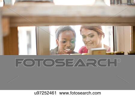 Two female friends looking through cafe window View Large Photo Image Stock Image - Two female friends looking through cafe window. Fotosearch