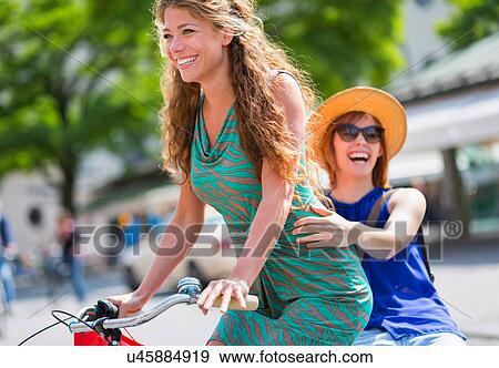 Two female friends riding bicycle View Large Photo Image Stock Photo - Two female friends riding bicycle. Fotosearch