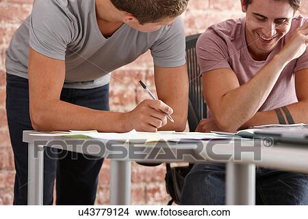 Two male colleagues, one making notes View Large Photo Image Picture - Two male colleagues, one making notes. Fotosearch