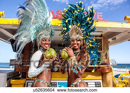 Picture - Two samba dancers drinking coconut drinks, Ipanema Beach, Rio, Brazil. Fotosearch