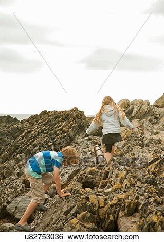 Two teenagers climbing over rocks View Large Photo Image Stock Photograph - Two teenagers climbing over rocks. Fotosearch
