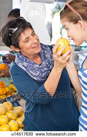 Stock Image - Two women buying fresh fruit in market. Fotosearch