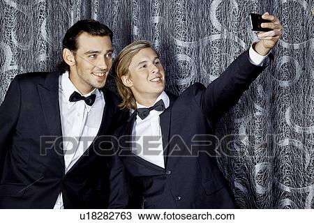 Stock Image - Two young men making self portrait on mobile phone. Fotosearch