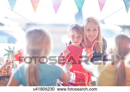 Stock Image - Two young sisters selling drink to brother from stall. Fotosearch