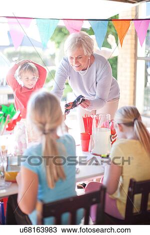 Stock Image - Two young sisters selling to grandma from stall. Fotosearch