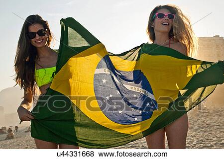 Stock Photo - Two young women having fun on beach with Brazilian Flag. Fotosearch