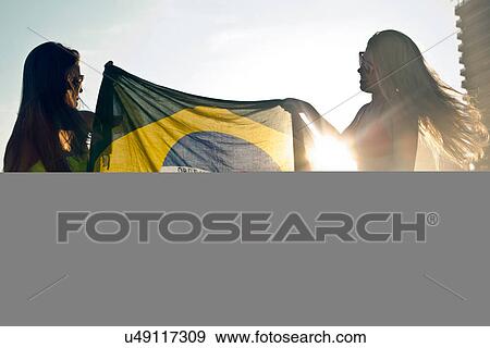 Stock Photo - Two young women with Brazilian Flag in sunlight. Fotosearch