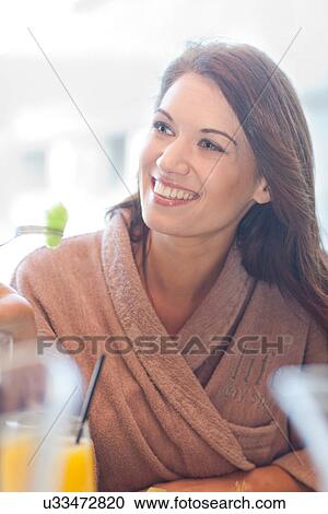 Stock Image - Woman at hotel poolside eating fresh fruit. Fotosearch