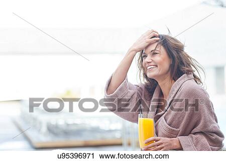 Stock Image - Woman at hotel poolside holding a glass of orange juice. Fotosearch