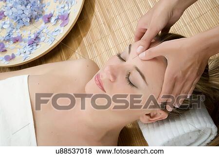 Stock Photo - Woman at spa having forehead massaged. Fotosearch