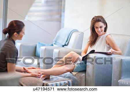 Stock Image - Woman having feet massaged in spa treatment room. Fotosearch