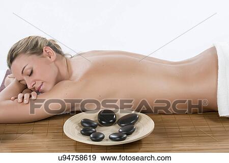 Stock Photo - Woman having hot stone therapy with eyes closed. Fotosearch