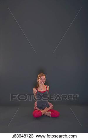 Stock Image - Woman in yoga pose on grey background. Fotosearch