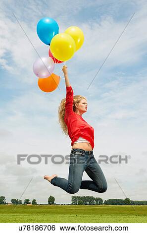 Stock Photograph - Woman jumping with balloons. Fotosearch