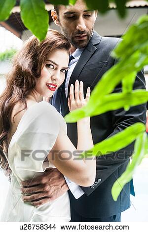 Woman looking over shoulder touching man's chest View Large Photo Image Picture - Woman looking over shoulder touching man's chest. Fotosearch