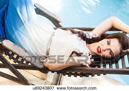 Stock Photo - Woman lying on sunlounger wearing sundress. Fotosearch