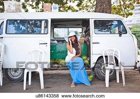 Stock Photo - Woman on cell phone by campervan. Fotosearch