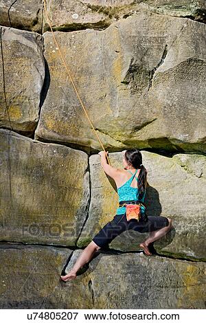 Stock Photo - Woman on top rope climbing sandstone butte. Fotosearch