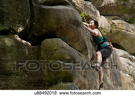 Stock Photo - Woman on top rope climbing sandstone butte. Fotosearch