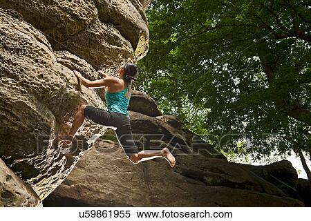 Stock Photography - Woman on top rope climbing sandstone butte. Fotosearch