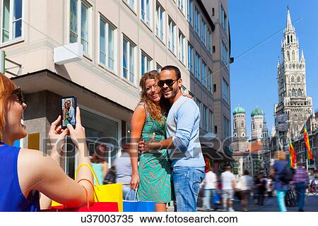 Stock Photography - Woman photographing couple in Munich Marienplatz, Munich, Germany. Fotosearch