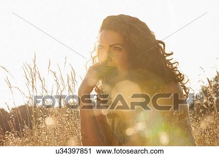 Stock Image - Woman sitting amongst wild flowers. Fotosearch