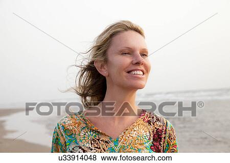 Woman smiling enjoying sea breeze View Large Photo Image Stock Photo - Woman smiling enjoying sea breeze. Fotosearch