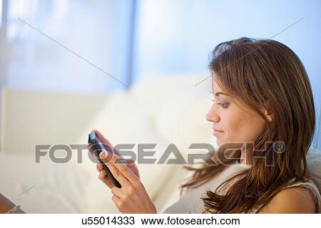 Stock Image - Woman using mobile phone in hotel lobby. Fotosearch