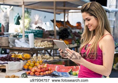 Stock Photo - Women using digital tablet in market. Fotosearch