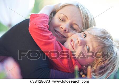 Stock Image - Young birthday boy hugging his mother. Fotosearch