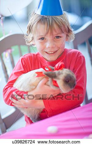 Picture - Young birthday boy hugging his rabbit. Fotosearch