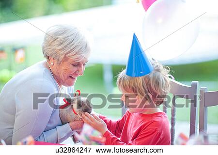 Stock Photo - Young boy at birthday party with present from gran. Fotosearch