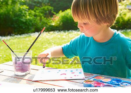 Stock Image - Young boy finger painting in garden. Fotosearch