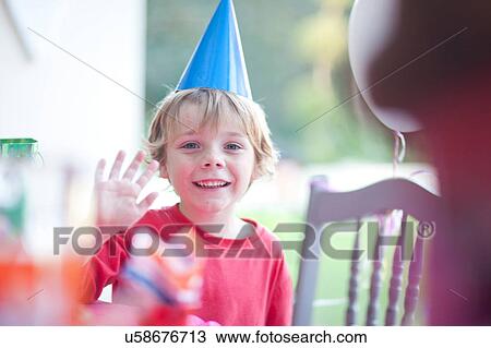 Stock Image - Young boy waving at birthday party. Fotosearch