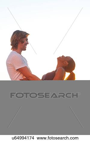 Picture - Young couple holding each other at sunset. Fotosearch