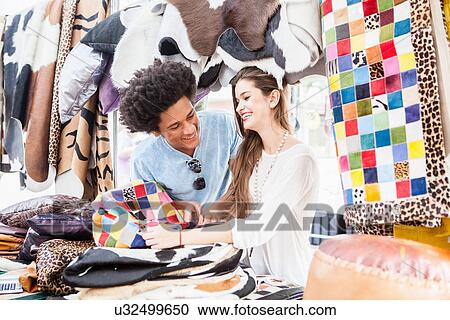 Stock Image - Young couple looking at souvenirs in market. Fotosearch