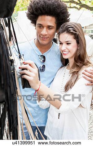 Young couple looking at souvenirs in market View Large Photo Image Stock Image - Young couple looking at souvenirs in market. Fotosearch