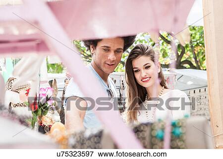 Stock Photo - Young couple looking at souvenirs in market. Fotosearch