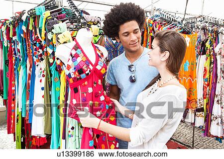 Young couple looking at sundresses in market View Large Photo Image Stock Photograph - Young couple looking at sundresses in market. Fotosearch