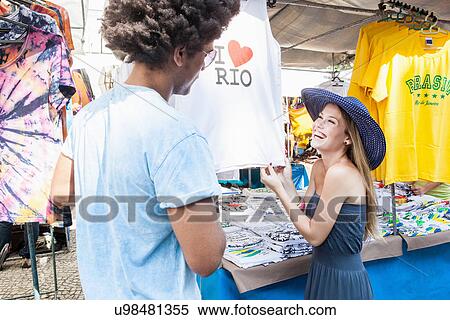Young couple looking at t-shirts in market View Large Photo Image Stock Photography - Young couple looking at t-shirts in market. Fotosearch