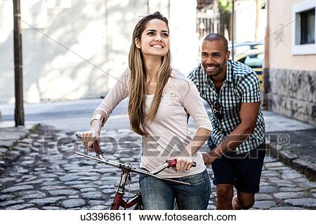 Young couple pushing bicycle in cobbled street, Rio de Janeiro, Brazil View Large Photo Image Stock Image - Young couple pushing bicycle in cobbled street, Rio de Janeiro, Brazil. Fotosearch