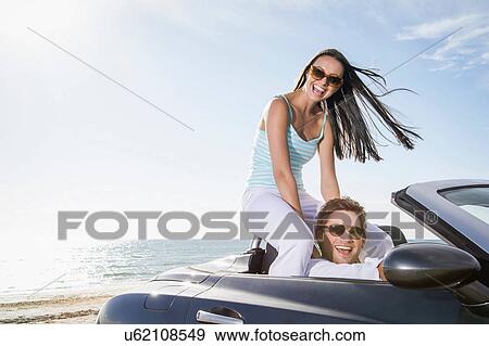 Young couple sitting in convertible sports car View Large Photo Image Stock Photo - Young couple sitting in convertible sports car. Fotosearch