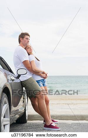 Young couple standing beside convertible sports car View Large Photo Image Picture - Young couple standing beside convertible sports car. Fotosearch