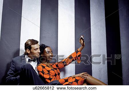 Stock Image - Young couple taking self portrait in club. Fotosearch