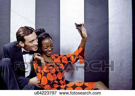 Stock Photo - Young couple taking self portrait in nightclub. Fotosearch