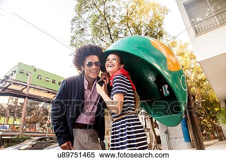 Stock Photography - Young couple using pay telephone. Fotosearch